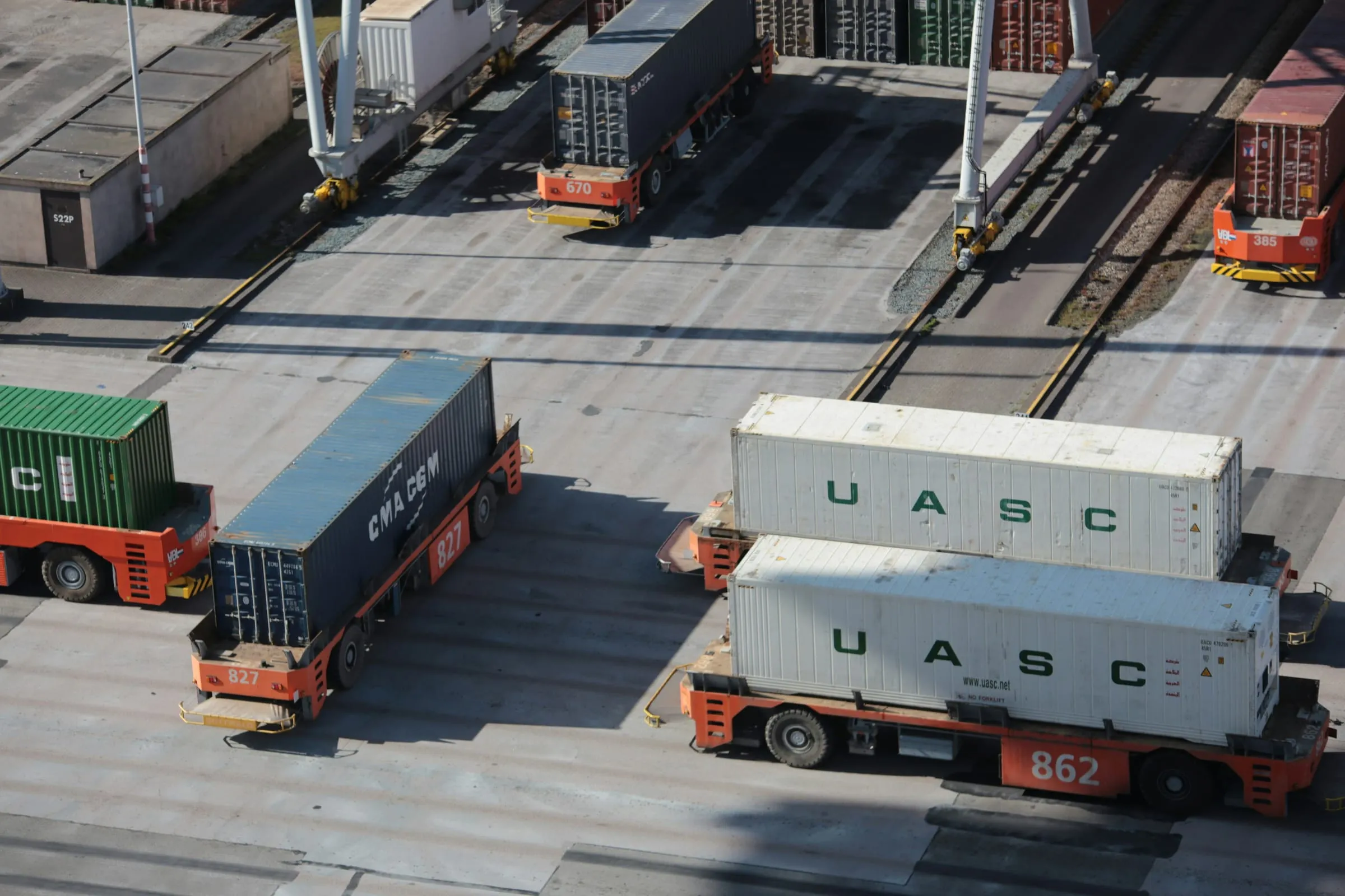 Autonomous container transporters moving cargo across a terminal yard, seen from above